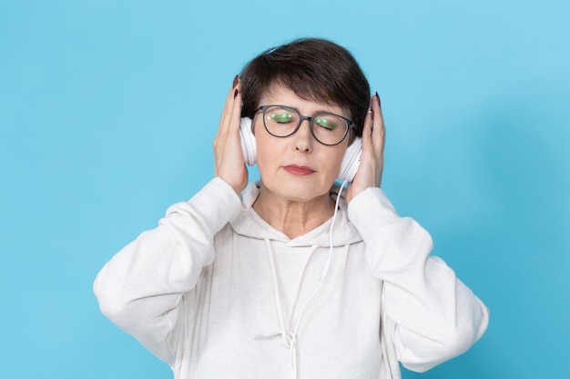 Frau mittleren Alters, die Musik auf blauer Wand hört. .