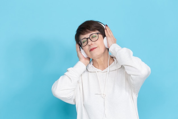 Frau mittleren Alters, die Musik auf bunter Wand hört.