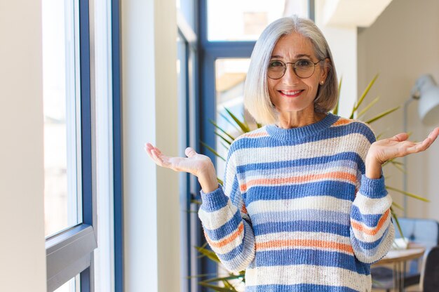 Frau mittleren Alters, die sich verwirrt und verwirrt fühlt, zweifelt, gewichtet oder verschiedene Optionen mit lustigem Ausdruck wählt