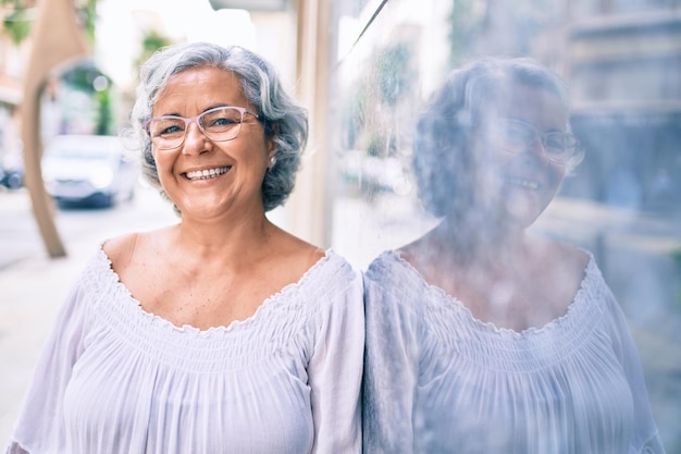Frau mittleren Alters mit grauem Haar lächelt glücklich im Freien