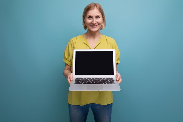 Frau mittleren Alters mit Laptop auf Studiohintergrund mit Kopierraum