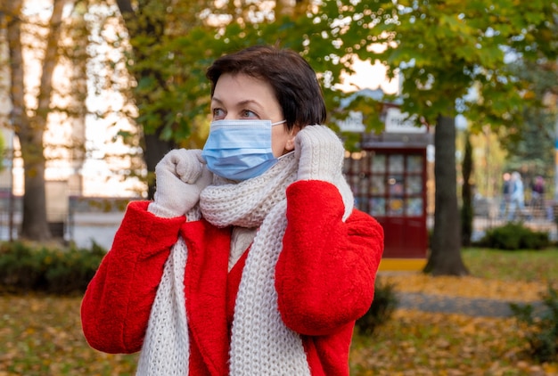 Foto frau mittleren alters mit schützender medizinischer maske auf ihrem gesicht geht im herbstpark