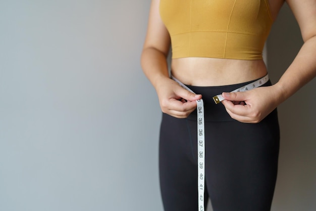 Frau möchte mit einem Zentimeter Gewicht verlieren. Formen Sie gesunde Bauchmuskeln und Diät, messen Sie die Taille mit Maßband nach Diät-Gewichtskontrolle