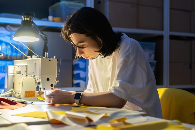 Frau Näherin Arbeit an Nähmaschine Nähen Kleidung erstellen neues Kollektionskonzept für kleine Unternehmen