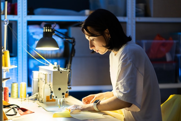 Frau Näherin Arbeit an Nähmaschine Nähen Kleidung erstellen neues Kollektionskonzept für kleine Unternehmen