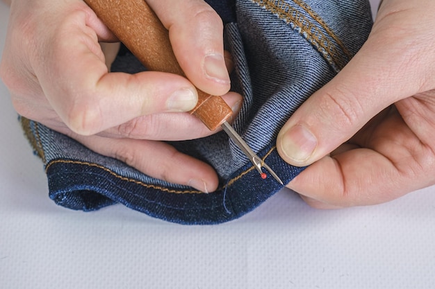 Frau Näherin reißt eine Naht auf einem Denim-Stoff mit einem Nahttrenner Näherin-Werkzeuge, die Kleidung reparieren, die Jeans ändert