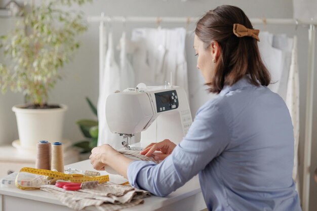 Frau näht Kleidung an einer Nähmaschine in einer Werkstattarbeit bei der Herstellung von Kleidungs- und Textilmustern und Stoffen zum Nähen