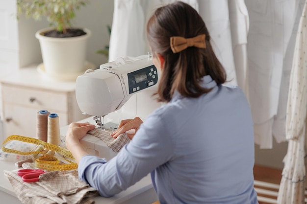 Frau näht Kleidung an einer Nähmaschine in einer Werkstattarbeit in der Herstellung von Kleidung und Textilien