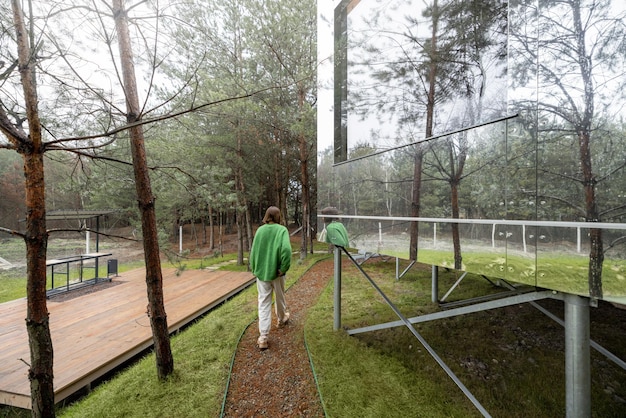 Frau nahe einem unsichtbaren Haus im Kiefernwald