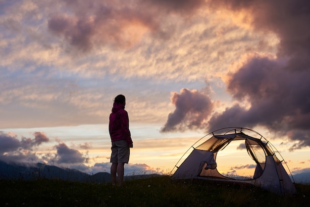Frau nahe Lager mit Sonnenuntergang am Berg