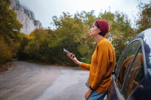 Foto frau neben einem auto und blick auf smartphone