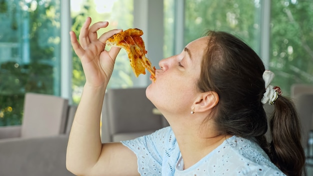 Frau nimmt ein Stück Pizza und isst gerne, Nahaufnahme