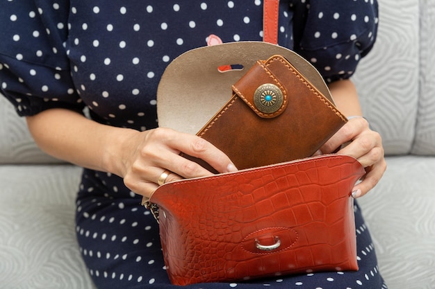 Frau nimmt eine braune Naturledergeldbörse aus ihrer Handtasche