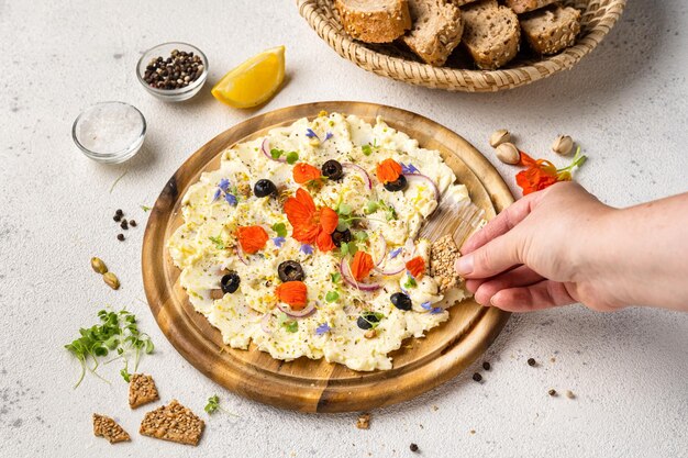 Foto frau nimmt mit der hand butter mit kräutern von einer holztafel, eine trendige vorspeise.