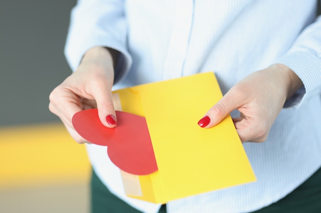 Frau nimmt Valentinstag in Form eines roten Herzens aus einem Umschlag Valentinstag Grüße und