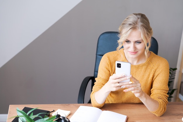 Frau nutzt Smartphone im Büro Ein schönes Mädchen schaut auf Handy
