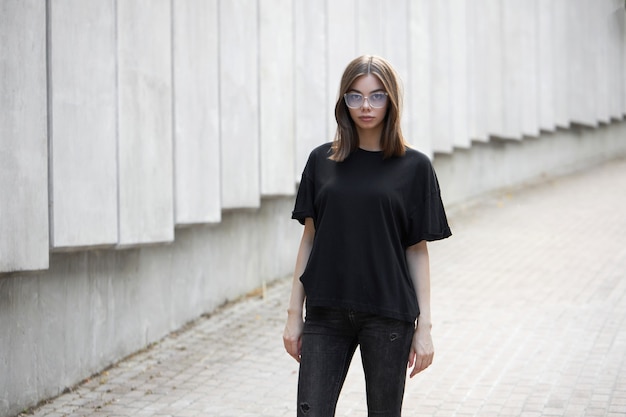 Frau oder Mädchen mit schwarzem, leerem Baumwoll-T-Shirt mit Platz für Ihr Logo, Mock-up oder Design im lässigen urbanen Stil