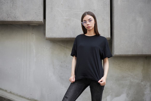Frau oder Mädchen mit schwarzem, leerem Baumwoll-T-Shirt mit Platz für Ihr Logo, Mock-up oder Design im lässigen urbanen Stil