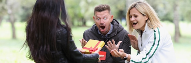 Foto frau öffnet geschenkbox und paar blickt auf glückliche überraschung und positive emotionen