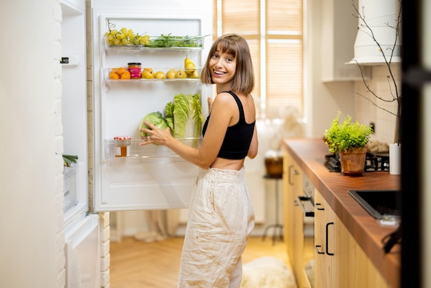 Frau öffnet Kühlschrank mit gesunden Lebensmittelzutaten