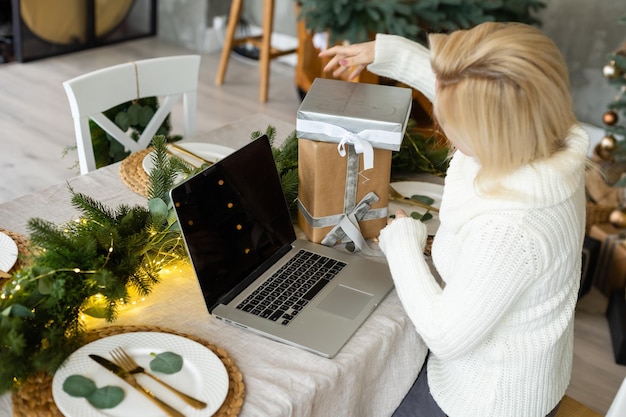 Frau online mit Laptop zu Hause im Wohnzimmer.