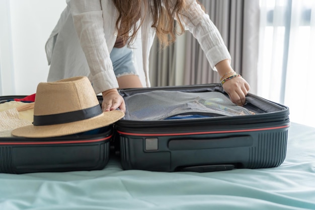 Frau packt Koffer auf dem Bett für eine neue Reise. Packliste für die Reiseplanung, die den Urlaub vorbereitet. Buchen Sie jetzt den Reisetransport