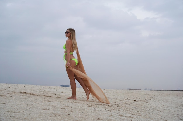 Frau posiert am Sommerstrand junge Blondine in einem Badeanzug