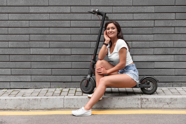 Frau posiert beim Sitzen auf Elektroroller