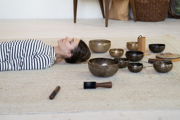 Foto frau praktiziert meditation mit tibetischen klangschalen therapie weibliche meditation von klangmassage sound