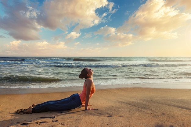 Frau praktiziert Yoga Asana Urdhva Mukha Svanasana am Strand