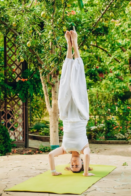Frau praktiziert Yoga im Sommergarten Salamba Sirsasana II Stativ Kopfstand