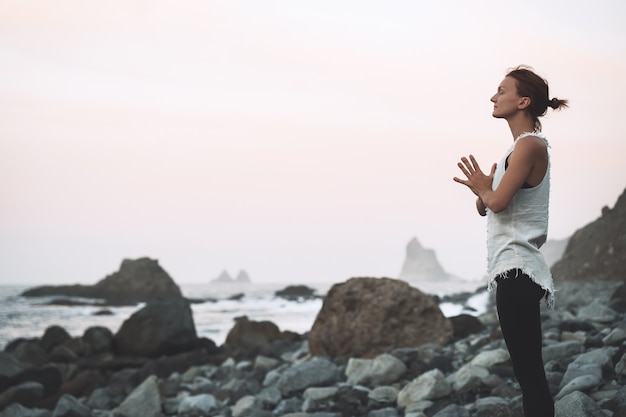 Frau praktiziert Yoga und Meditation am schönen wilden Strand