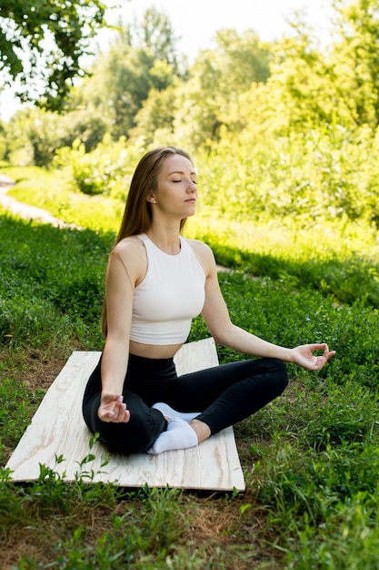 Frau praktiziert Yoga und meditiert in der Lotussitzung am Strand