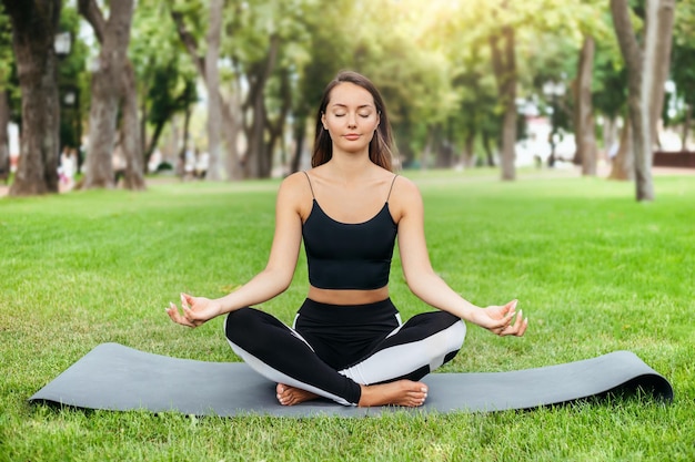 Frau praktiziert Yoga während des Trainings im Park. Gesunder Lebensstil. Körperliche Bewegung