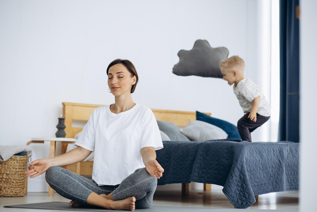 Frau praktiziert Yoga zu Hause mit weinendem Kind