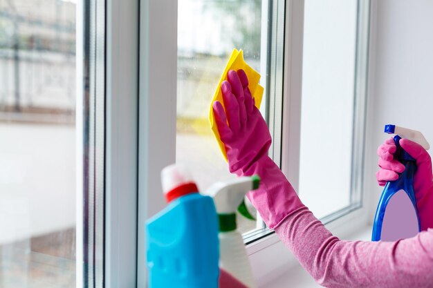 Frau putzt ein Fenster mit gelbem Tuch