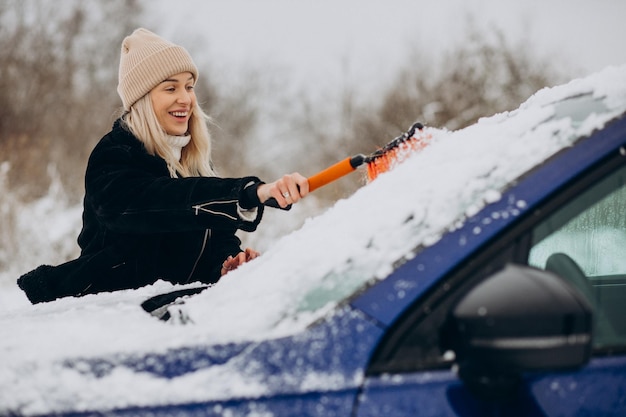 Frau putzt ihr Fensterauto vom Schnee