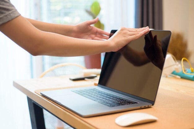 Frau putzt Laptop durch Alkoholspray