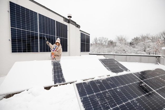 Frau reinigt Sonnenkollektoren vom Schnee