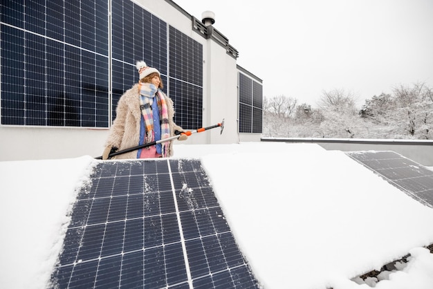 Frau reinigt Sonnenkollektoren vom Schnee