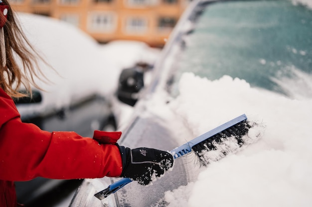 Foto frau reinigung schnee von seinem auto im winter schneefall eiskratzen winterfensterreinigung