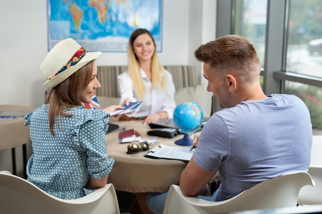 Foto frau reisebüro gibt ein paar pässe mit flugtickets im reisebüro.