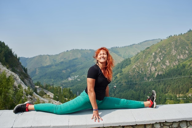 Frau Reisende sitzt auf einer Schnur in Zailiysky Alatau in Almaty auf dem Hintergrund der Berglandschaft des Sommers Kasachstan, genießt die Natur und sonniges Wetter