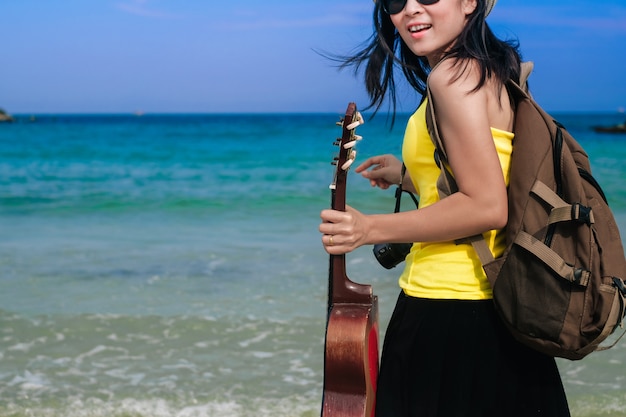 Frau Reisenden haben eine Tasche und Gitarre am Strand stehen
