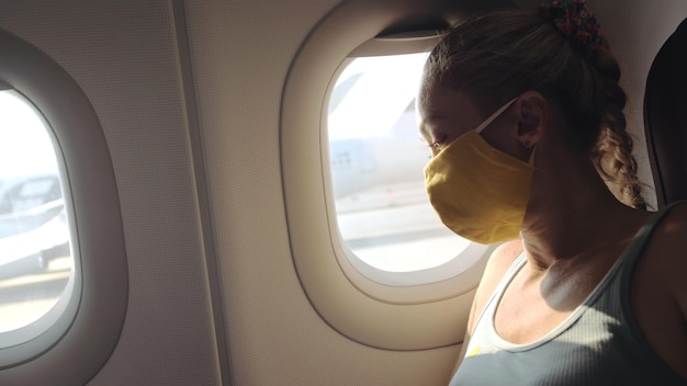 Frau reist kaukasisch im Flugzeug mit medizinischer Schutzmaske Touristin im Flugzeug mit Schutzmaske Konzept Virenschutz Coronavirus-Epidemie sarscov2 covid19 2019ncov