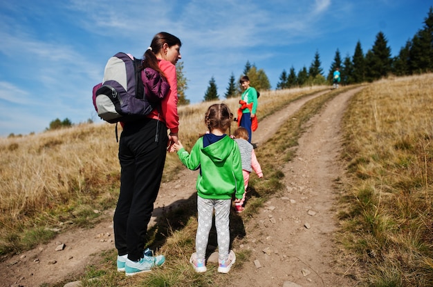 Frau reist mit Kindern. Mama in den Bergen. Klettern Sie mit Kindern auf den Gipfel des Berges. Mit dem Rucksack nach oben geklettert.