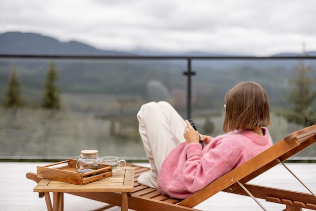 Frau ruht auf der Terrasse in den Bergen