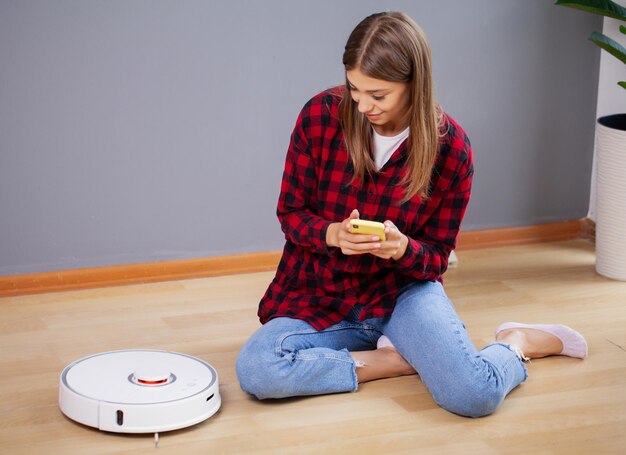 Frau ruht sich aus, während der Roboterstaubsauger ihre Arbeit zu Hause erledigt