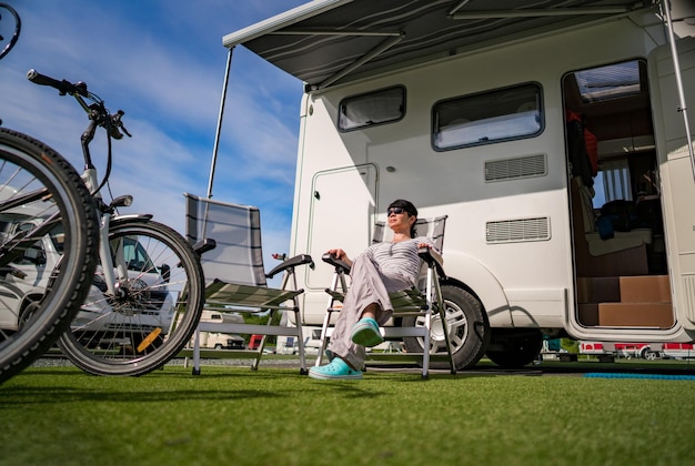 Frau ruht sich in der Nähe von Wohnmobilen in der Natur aus. Familienurlaubsreisen, Urlaubsreise im Wohnmobil, Caravan-Autourlaub.