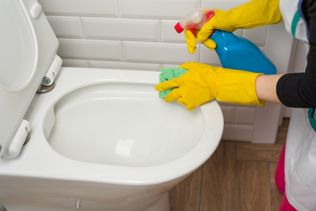 Frau säubert im badezimmer. toilette waschen.